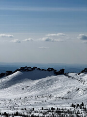 Snow-covered mountain ridge under blue sky with scattered clouds.