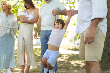 Fototapeta premium Family generation enjoying day helping toddler swinging outdoors