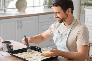 Young man preparing cookies in kitchen