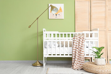 Interior of children's bedroom with crib, lamp and folding screen