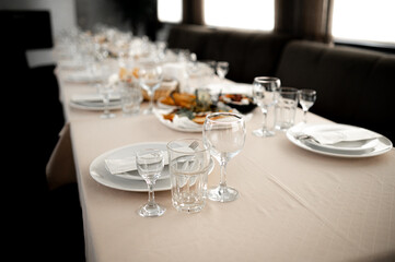 empty wine glasses on banquet served table in open air in rays of setting sun
