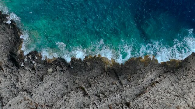 Top Down Aerial Drone View showing the power of the ocean with waves hitting the rocky coast of Zakynthos Greece in the turquoise Ionian Sea