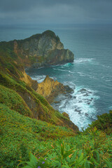 Muroran, Hokkaido, Japan - Oct 04 2024, vertical aerial view of the picturesque Pacific ocean coast with sharp cliffs and high mountain slopes, in a storm, it's raining, at daytime, Muroran, Japan