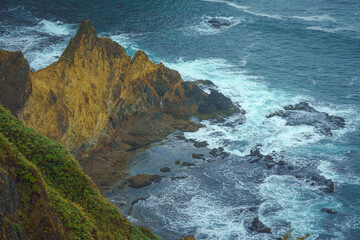 Muroran, Hokkaido, Japan - Oct 04 2024, panoramic aerial view of the picturesque Pacific ocean coast with sharp cliffs and high mountain slopes, in a storm, it's raining, at daytime, Muroran, Japan
