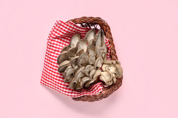 Wicker basket with fresh oyster mushrooms on pink background