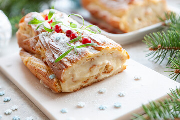 Festive homemade log roll with custard against a backdrop of Christmas decorations