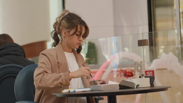 female artist annotating with vibrant markers, serene woman sketching and arranging thoughts on planner pages, quiet public area where woman peacefully journals using colorful pens and planner