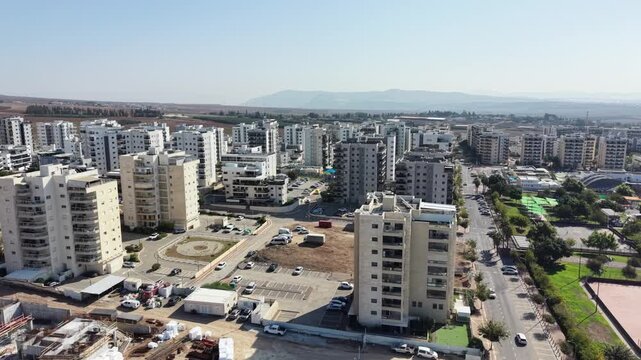 Aerial drone view of Afula, a city in northern Israel, showing urban neighborhoods, residential buildings, roads, and surrounding landscape. Modern Israeli cityscape captured from above, highlighting 