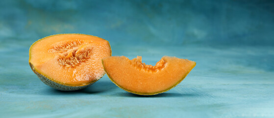 A sliced ​​melon with juicy orange flesh and numerous seeds on a blue background. Copy space.