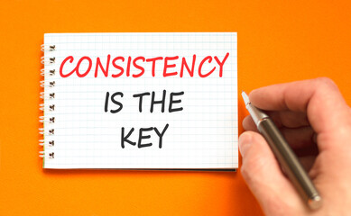 Fototapeta premium Consistency is the key symbol. Concept words Consistency is the key on beautiful white note. Beautiful orange background. Businessman's hand. Business consistency is the key concept. Copy space.