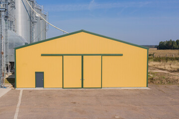 Fototapeta premium Yellow Industrial Farm Warehouse Building With Metal Sheet Exterior on a Sunny Day