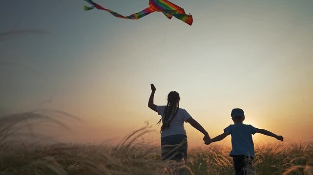 Children walk together in golden sunset field. Girl and boy hold hands flying kite. Siblings share child play moments. Field breeze lifts kite high in air. Sunset joy for girl boy child in open space