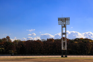 Stadium lights pole against blue sky, daytime.