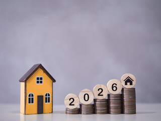 Miniature house, Wooden blocks with the number 2026 on stack of coins. The concept of saving money...