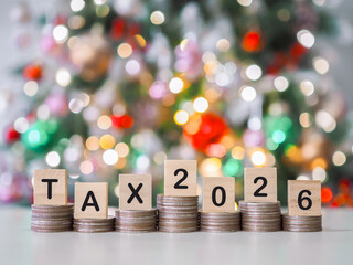 Wooden blocks with the word TAX and number 2026 on stack of coins with shiny light for Christmas background. The concept of saving money for prepare to pay tax in year 2026