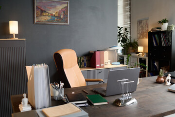 Empty therapist office showing modern workspace with desk, laptop, files, books and decor, suggesting professional therapy environment without people present