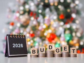 2026 desk calendar and Wooden blocks with the word BUDGET on stack of coins with shiny light for Christmas background. The concept about budget planning and allocation in year 2026