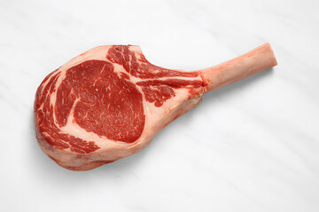 Fototapeta premium Raw tomahawk ribeye steak displayed on elegant white marble highlighting premium beef quality gourmet cooking preparation luxury dining and butcher craftsmanship