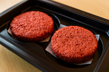 Two uncooked plant based burger patties in a black plastic tray representing vegan alternatives sustainable food choices and modern diets