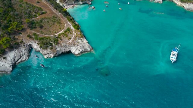 Cinematic Aerial Drone View of Makris Gialos Beach in Zakynthos Greece with turquoise water rocky coves coastal road and boats in the Ionian Sea