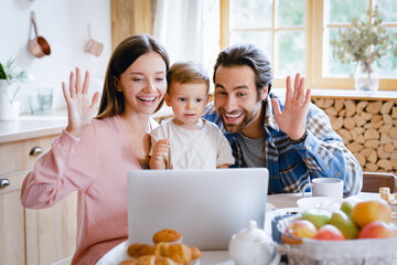 Happy young caucasian family having videocall conference conversation online at home on laptop, talking with relatives, grandparents with little small child kid toddler new born baby infant