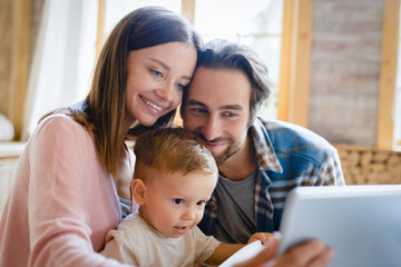 Closeup image of caucasian young happy family taking selfie photo on tablet, having videocall conversation conference with relatives grandparents at home kitchen. Childcare and parenthood
