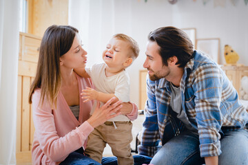 Parents take care of child. Little small crying shouting baby child kid infant toddler newborn feeling hungry, needs to change diapers, suffering from colics and teething. Parenthood