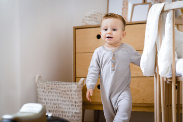 First steps. Little small caucasian child kid toddler boy son walking at home, learning and exploring the world. Parenthood and child care concept. Advertisement for children's products, clothing
