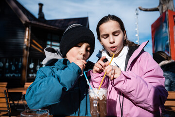 Children sharing hot chocolate at a winter ski resort cafe