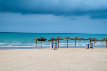 Wide sandy beach with calm sea and blue sky, coastal city on the horizon creating a peaceful seaside landscape with copy space.