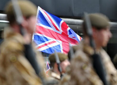 Soldiers march past a Union Flag. 