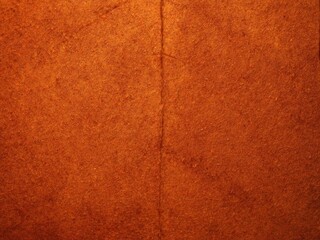 Fototapeta premium Textured reddish-brown surface with vertical seam and fibrous creases 