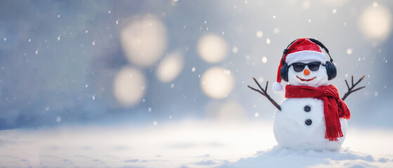 Fototapeta premium Cute snowman in Santa hat and headphones on snowy field, wide winter banner with copy space, Christmas background for holiday greeting or seasonal promotion