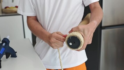 A man is renovating a cat's house by replacing a new jute thread.
