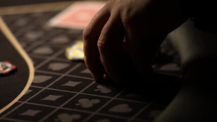 Close up cinematic video of casino poker player hand carefully placing stacking and adjusting betting chips on patterned felt table during intense live gambling round