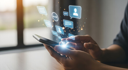 Hands holding smartphone with social media icons and chat bubbles floating up