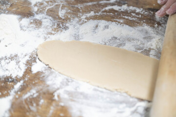 Homemade cookie baking process with dough, rolling pin and cutters. Step by step preparation of festive cookies on wooden table, cozy home kitchen, family baking concept.
