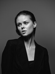 Black and white portrait of a young woman in a dark blazer with serious expression and slicked-back...