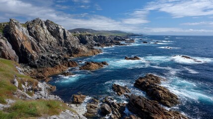 Fototapeta premium A coastal landscape featuring rugged cliffs meeting the blue ocean under a bright, partly cloudy sky. The rocky shore extends