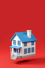 Stylized 3D Two-Story House with Blue Accents and White Chimney, Porch with Stairs, on Solid Red Background with Copy Space for Title or Message