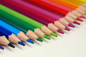 New wooden colored pencils of rainbow colors, perfectly sharpened, lie on table