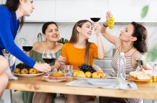 During tableful and birthday party, woman sitting on table, chatting sweetly, discussing and telling news, sharing plans with female friends. Women celebrates housewarming party with relative.