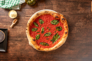 Neapolitan pizza marinara with basil on wooden table