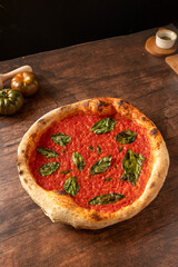 Neapolitan marinara pizza with fresh basil on dark wood table