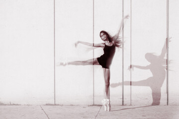 Artistic motion blur of a 12 year old girl ballerina dancing in pointe shoes against a concrete wall © greiss design