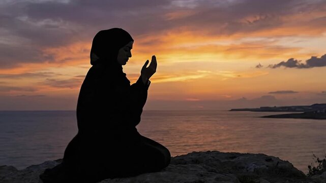A serene silhouette of a person kneeling by the tranquil ocean, hands raised in a gesture of deep prayer or profound contemplation. This individual, adorned in traditional long robes and a head coveri