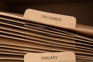 Stacked brown file folders labeled by month to keep reports and documents organized 