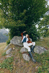 Fototapeta premium Woman in nature relaxing under a tree on rocks in a countryside meadow, wearing boots and casual outfit, lying back and enjoying peaceful outdoor leisure and scenic landscape.