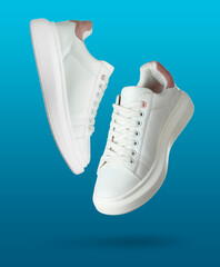 White sneakers in air on blue gradient background