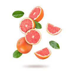 Fresh grapefruits and green leaves falling on white background
